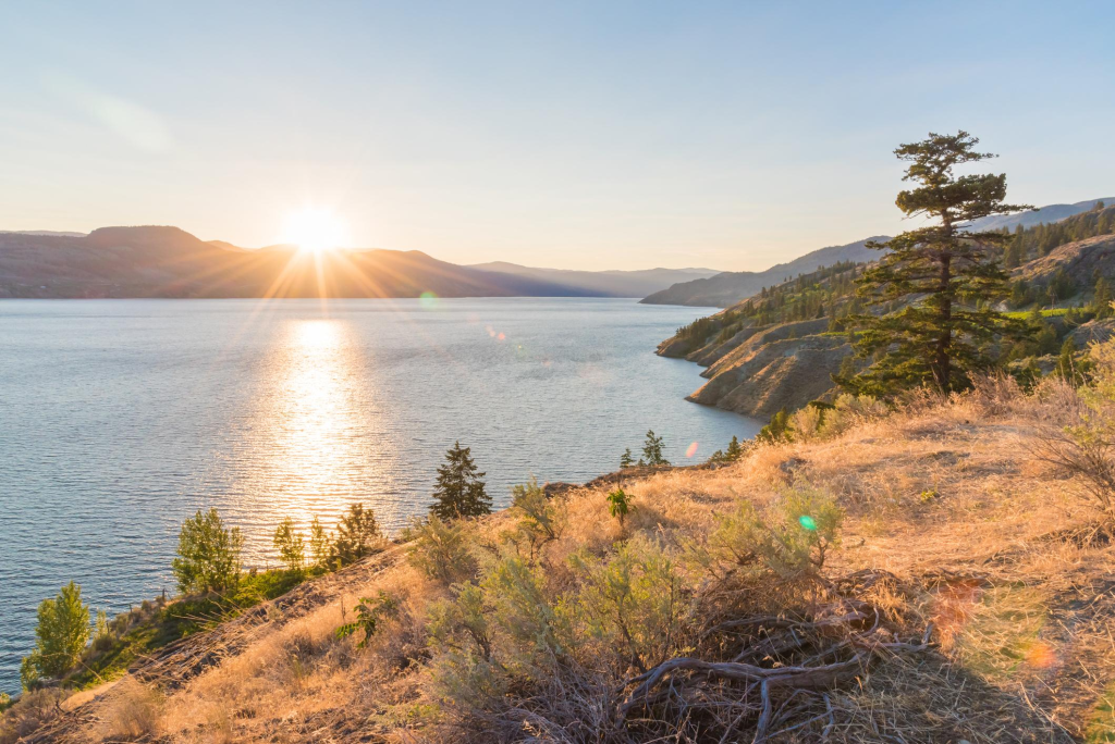 Sun setting behind mountains on Okanagan Lake on summer evening on Naramata Bench