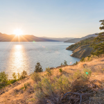 Sun setting behind mountains on Okanagan Lake on summer evening on Naramata Bench