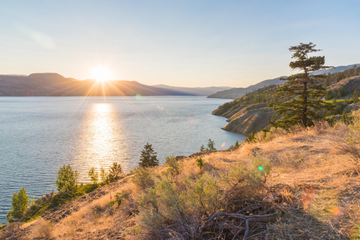 Sun setting behind mountains on Okanagan Lake on summer evening on Naramata Bench